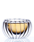 A transparent, ribbed glass bowl featuring a golden hue at the base, embodies an elegant and modern design similar to the Double-Walled Rippled Tea Cup. The empty bowl is displayed against a plain, white background, emphasizing its reflective and intricate texture.