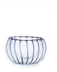 A clear, double-walled tea cup with vertical ripples, resembling a pumpkin shape, is set against a plain white background. The cup appears empty and lightly reflects light, creating a delicate, elegant appearance perfect for tea ceremonies.