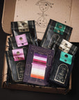An open cardboard box reveals five bags of Self-Guided 14 Day Ceremonial Sensory Tea Cleanse Kits from Club Magic Hour, each in different colors: pink, green, gold, purple, and teal. In the center is a colorful card labeled "The Spectrum of Possibility" showing various flavor profiles. The interior has starry illustrations reminiscent of a Magic Hour Tea set.