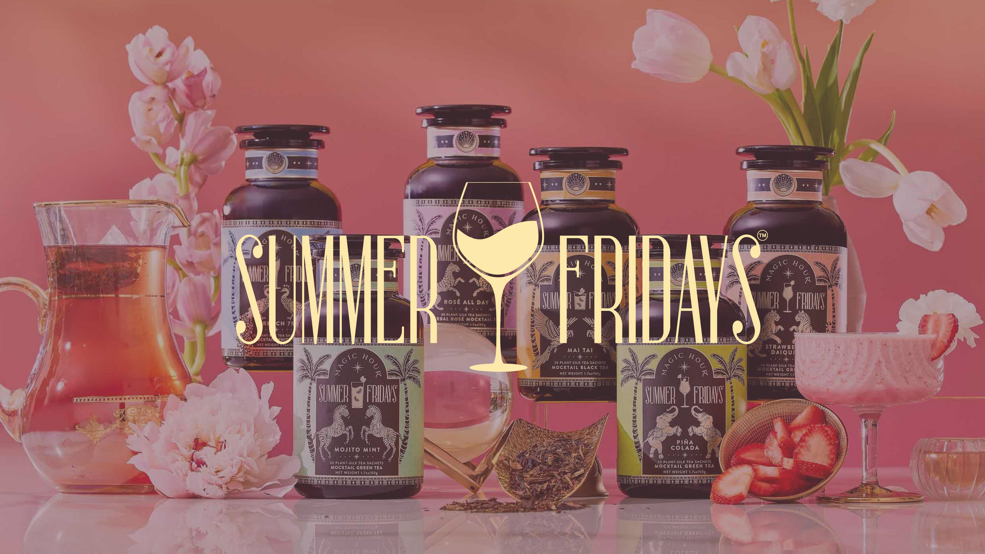 Three black glass supplement bottles with pastel labels are arranged diagonally on a pink surface, surrounded by a clear teapot, a cup with flower petals, and pink orchid flowers.