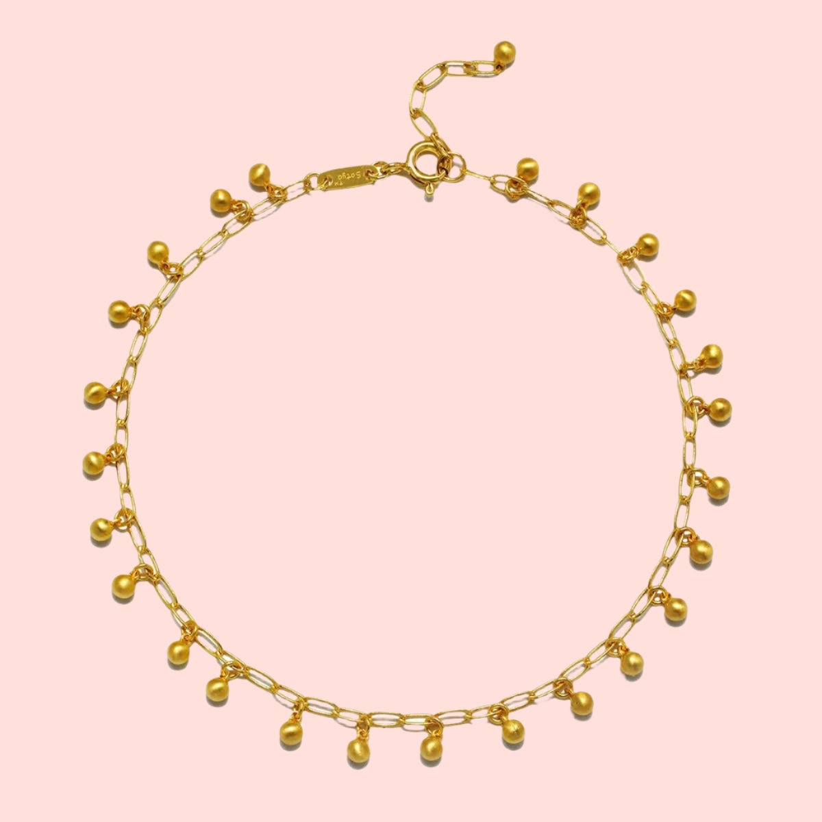 The Joyful Anklet is a delicate 18k gold plated anklet with small dangling gold beads spaced along a fine oval cable chain, finished with an adjustable clasp.