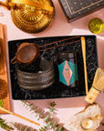 Matcha 1111 : Gift Set in a black box featuring a tea tin, black ceramic bowl, fine-mesh strainer, and bamboo whisk, arranged with a gold teapot, cups of matcha, and a crystal tea light holder.