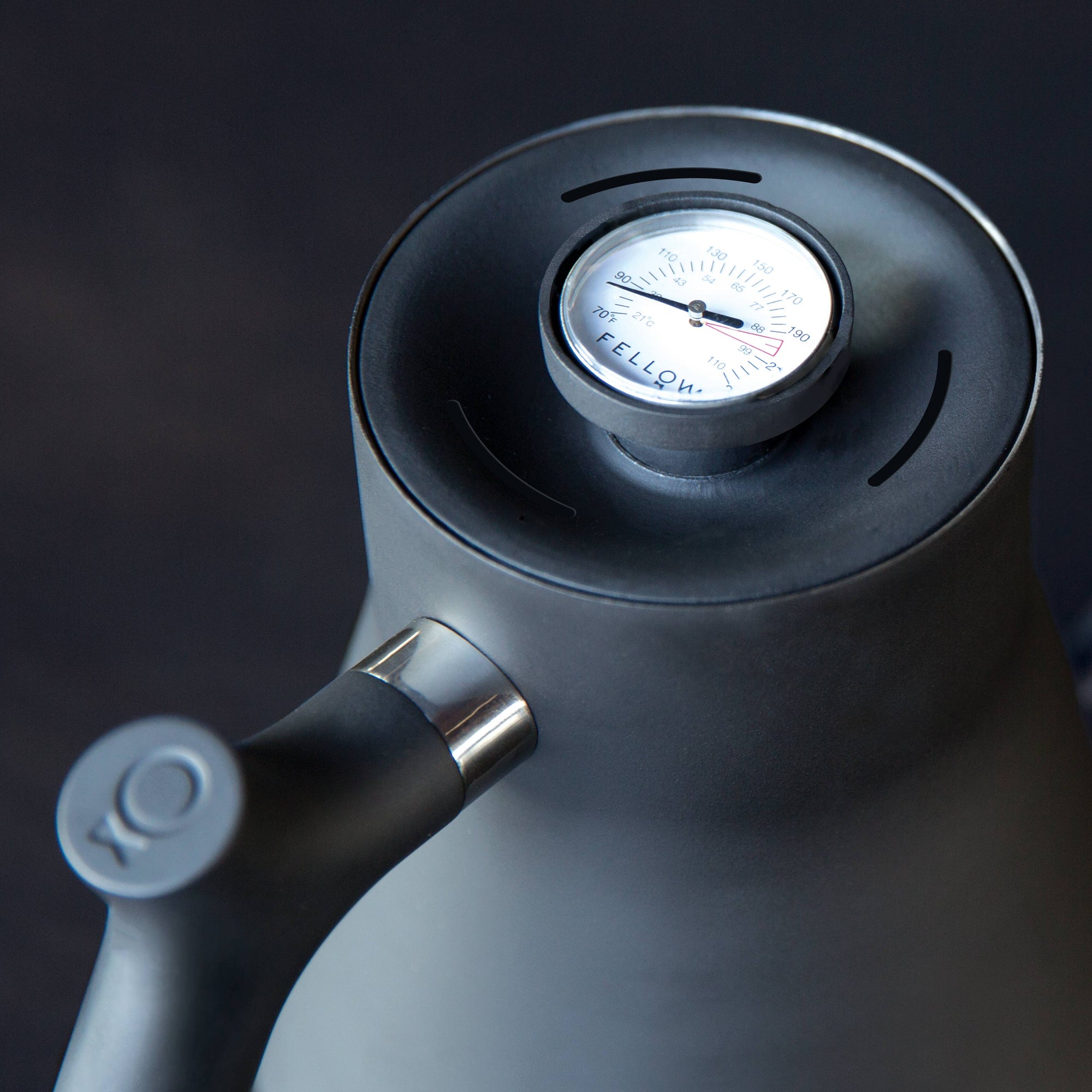 A close-up of the Stagg Pour-Over Kettle (Stovetop), a black kettle with a precision spout and built-in brew-range thermometer on the lid displaying the Fellow brand, set against a dark background.