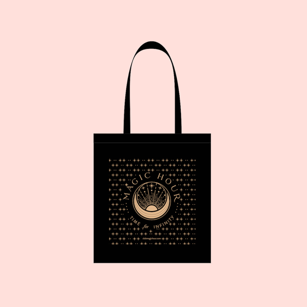 The Magic Hour Tote Bag, measuring 14x15 inches, features an intricate gold design of a central circle with rays and celestial symbols on a black cotton background. The light pink backdrop highlights the text &quot;Magic Hour&quot; with the smaller words &quot;Time of Infinite,&quot; making it perfect for carrying during enchanted moments on the go.