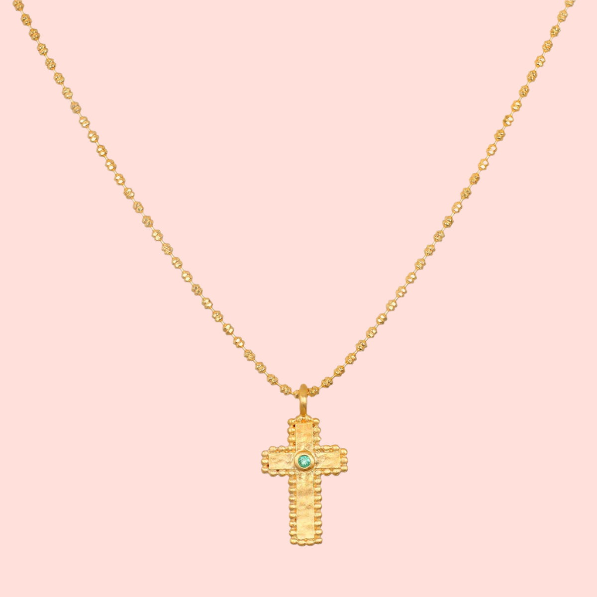 The 16" Emerald Dot Cross Pendant Necklace with a 3" extension features a beaded chain and a textured cross pendant accented by a small emerald, shown on a white background—a timeless piece of faith jewelry.