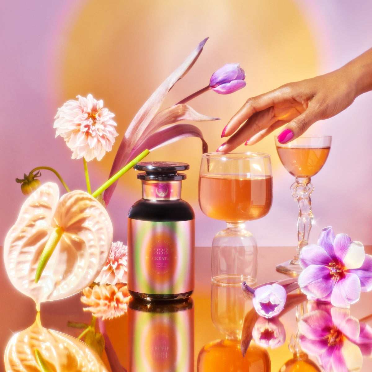 The vibrant display features the School of Magic Tea Subscription Box in a colorful bottle set among elegant orchids and calla lilies. A pink-nailed hand gently touches the glass jar with golden liquid, reminiscent of wellness tea, against a warm, gradient background.