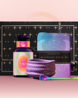 The Angel Numerology Fruit & Flower Tea Gift Set includes a star-patterned box, colorful "333 Angel" bottle, folded purple towel, purple and blue card, and a small green spoon—beautifully arranged on a pink background.