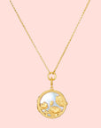 The Take Flight Butterfly Pearl Locket Necklace 18” features a gold chain and a round, mother of pearl pendant adorned with intricate flowers and a butterfly on an iridescent background.