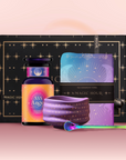 The Angel Numerology Fruit & Flower Tea Gift Set includes a black and gold box, a purple and orange labeled tea jar, a blue and purple tea towel, a matching purple bowl with gold stars, and a multicolored spoon.