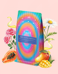 A vibrant tea bag labeled "555: Celestial Harmony: Papaya-Mango-Rose Tea with Ashwagandha" sits amid illustrated roses, daisies, papaya, and mango, evoking relaxation with swirling yellow ribbons on a soft pink background.