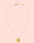 The Abundant Grounding Tree Necklace features a gold chain with a round pendant engraved with a tree of life design, symbolizing grounding. Shown on a white background.