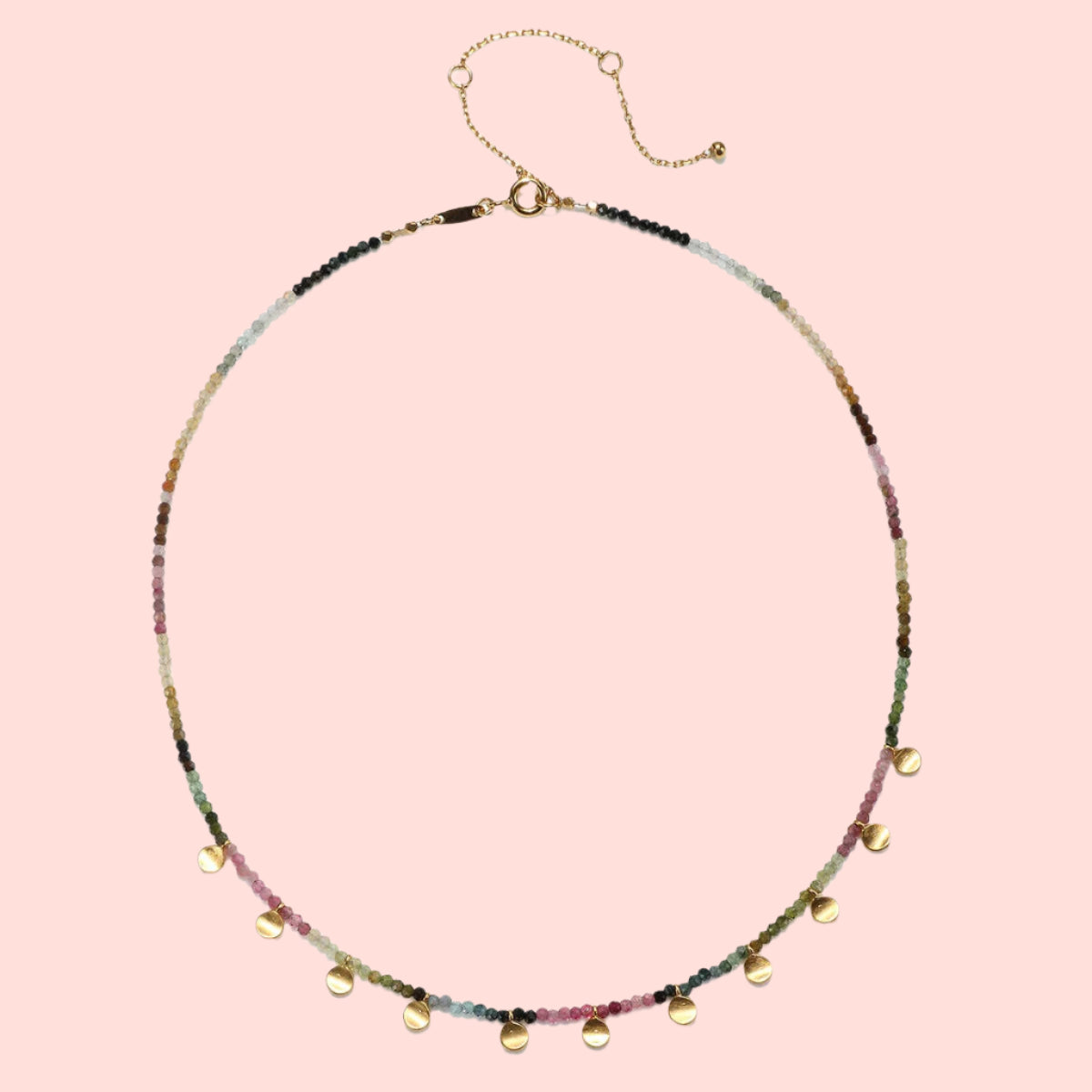 The Tourmaline Gold Moon Choker Necklace features a delicate gold-plated chain with multicolored round beads, seven gold disc charms, and an adjustable clasp—perfect for those seeking a subtle touch of elegance.