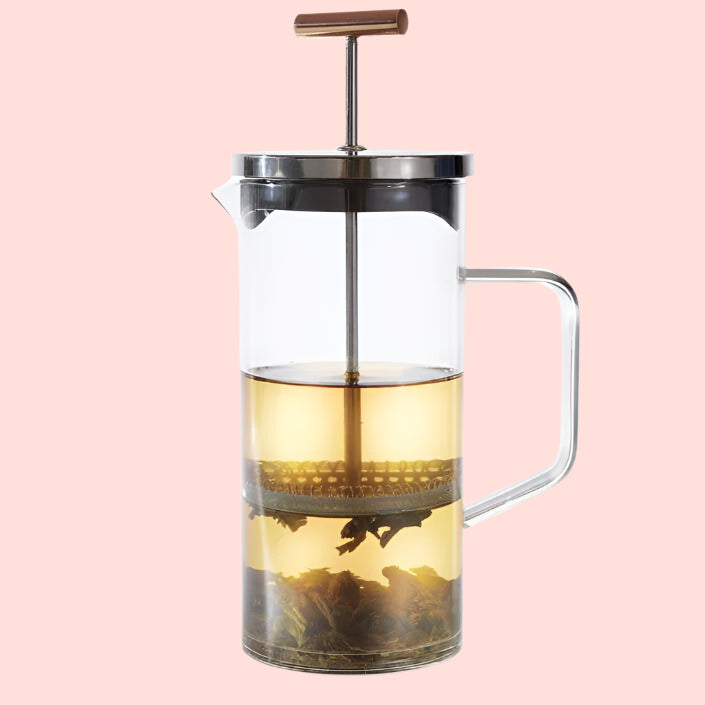 The Teabloom Pekoe Tea Press With Copper Handle (34 oz) sits against a white background, showcasing its metal plunger and elegant copper handle. Its clear design enhances tea flavor, making it ideal for tea connoisseurs.