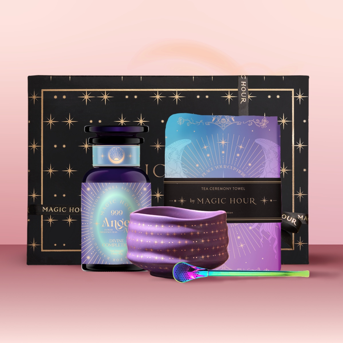 The Angel Numerology Fruit &amp; Flower Tea Gift Set includes a black and gold starry box, purple “Angel” bottle, star-patterned cloth, blue-purple tea towel, and colorful spoon—all beautifully displayed on a pink background.