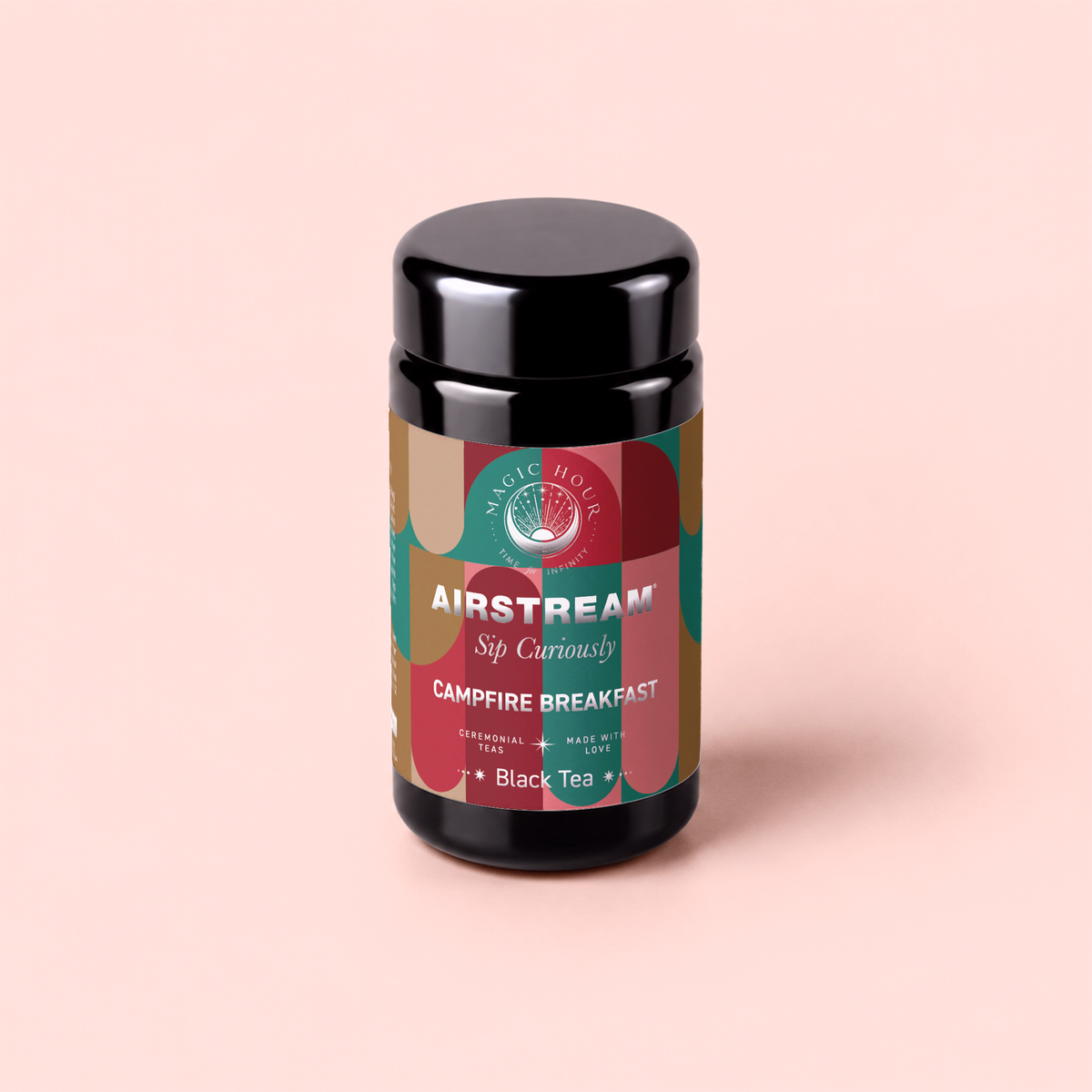 A black tea canister labeled “Campfire Breakfast: Golden Tipped Assam, Puerh &amp; Lapsang Souchong Pine Smoked Connoisseur’s Cup for Nostalgic Mornings” sits on a pastel pink background. The eye-catching label features the phrases “Sip Curiously” and “Black Tea,” along with green, red, and tan design accents. This smoky blend’s inclusion of lapsang souchong makes it a bold and flavorful coffee alternative for those seeking an adventurous start to their day.