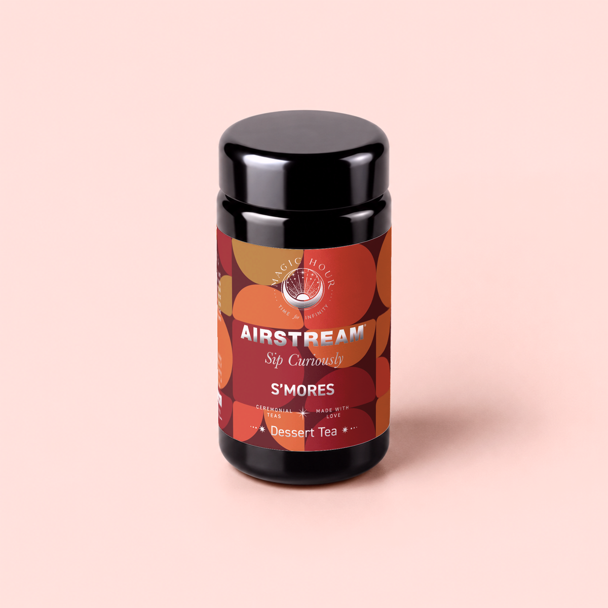A black tea canister labeled “S’mores: Chocolate Herbal Dessert Tea for the Kid in All of Us,” featuring an orange and brown circular pattern on a light pink background, offers a cozy caffeine-free experience crafted with organic rooibos for a delightful herbal tea twist.