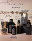 An arrangement of various black and gold Magic Hour tea containers under a branch's shadow. The containers, filled with Aquamarine Dream - Soothing Herbal Ayurvedic Adrenal Tonic, are labeled: Luxe Refill Pouch, Big Magic Apothecary Jar, Violet Glass Traveler Jar, Violet Glass Apothecary Jar, Petite Apothecary Jar, and Sampler Pouch. The text reads "Magic Hour Tea Size Guide.