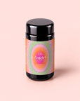 A black jar with a vibrant, radiant label reading “333: Mango-Lemon Balm-Rose Herbal Tea with Passionflower” on a light pink background. The label features pink, orange, and green gradients with sunburst patterns, evoking the essence of divine creativity and inspired by an Archangel Jophiel elixir.