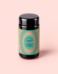 A black jar with a green and orange label reading “888: Lemon-Jasmine-Vanilla Herbal Tea”, “Magic Hour”, and “Golden Gateway” stands on a pale pink background, evoking the essence of abundance tea inspired by Archangel Michael.