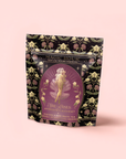Aphrodite's Alchemy - Damiana & Rose White Tea features a Greek goddess-inspired illustration and floral patterns on a black and gold decorative package.