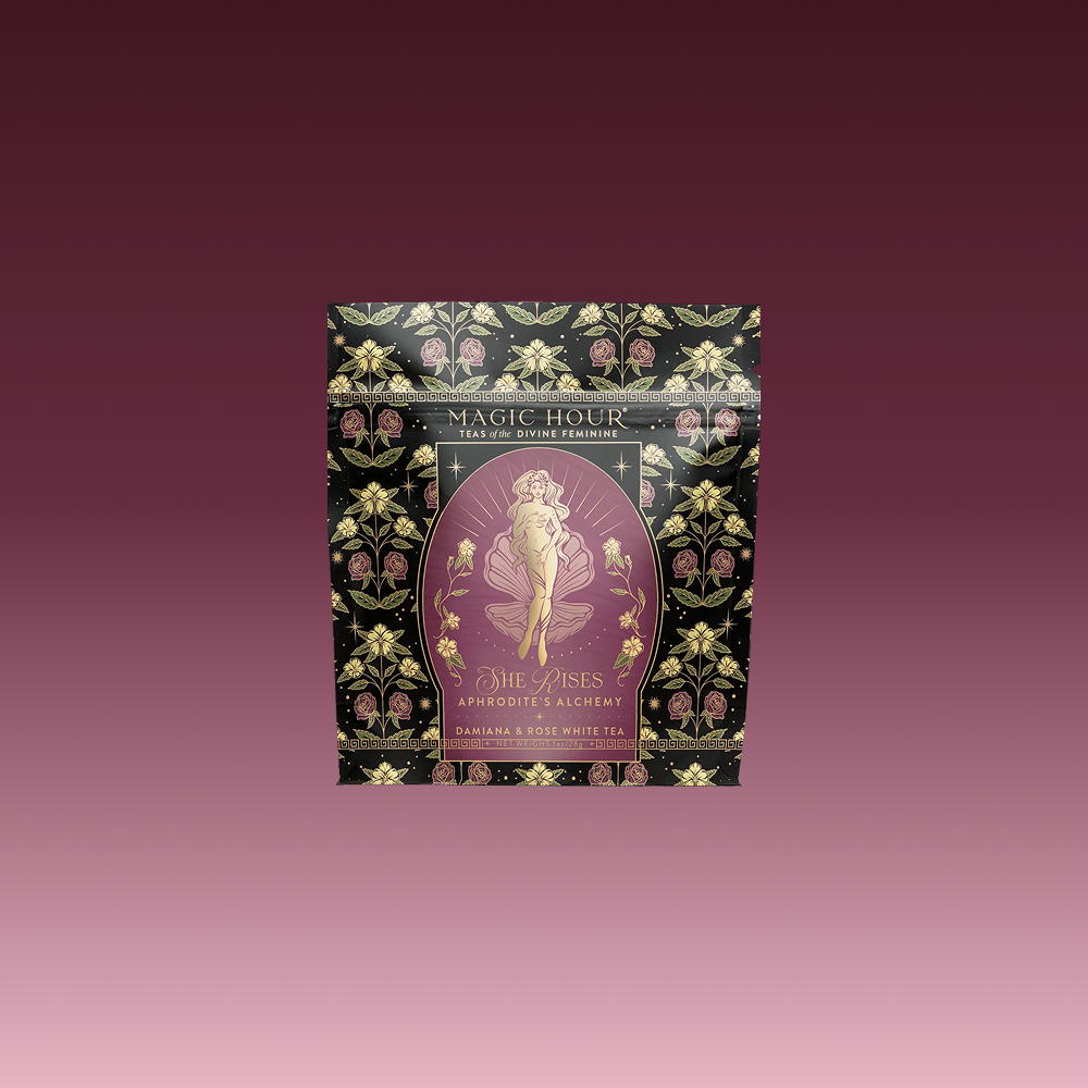 A beautifully designed tea package labeled "Aphrodite's Alchemy: Damiana & Rose White Tea," featuring an illustrated goddess of love from Greek mythology, surrounded by flowers and elegant gold accents.