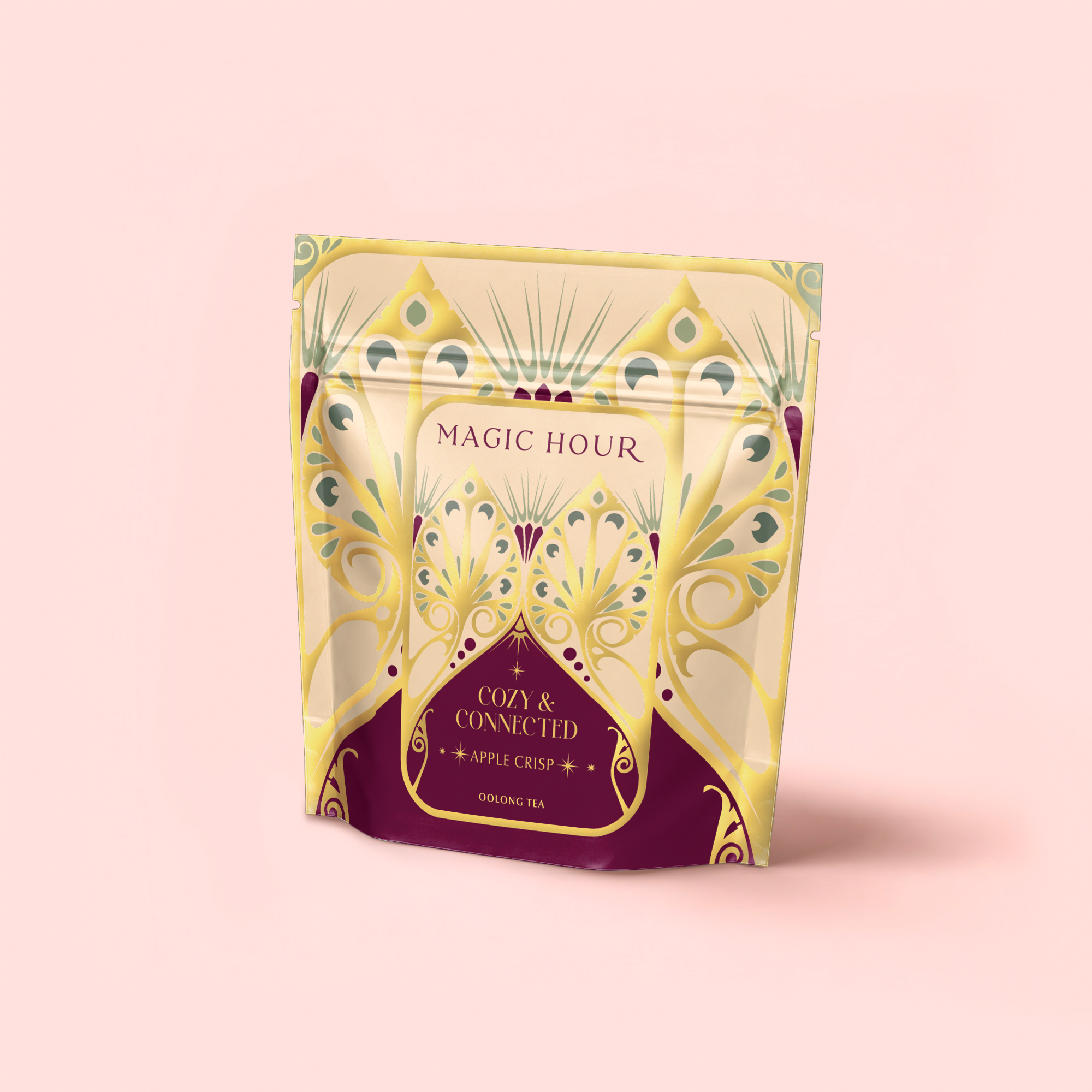 A decorative stand-up pouch with a pale yellow and purple design labeled "Magic Hour" and "Apple Crisp Oolong: Cozy & Connected," featuring this autumn tea blend against a light pink background.