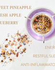 A top-down view of a tea blend in a purple-rimmed infuser, with scattered dried ingredients including pieces of pineapple, apple, and blueberries. Text labels read: "Magic Hour Aquamarine Dream - Soothing Herbal Ayurvedic Adrenal Tonic, Sweet Pineapple, Fresh Apple, Blueberry, Energy, Restful Sleep, Anti-Inflammatory.