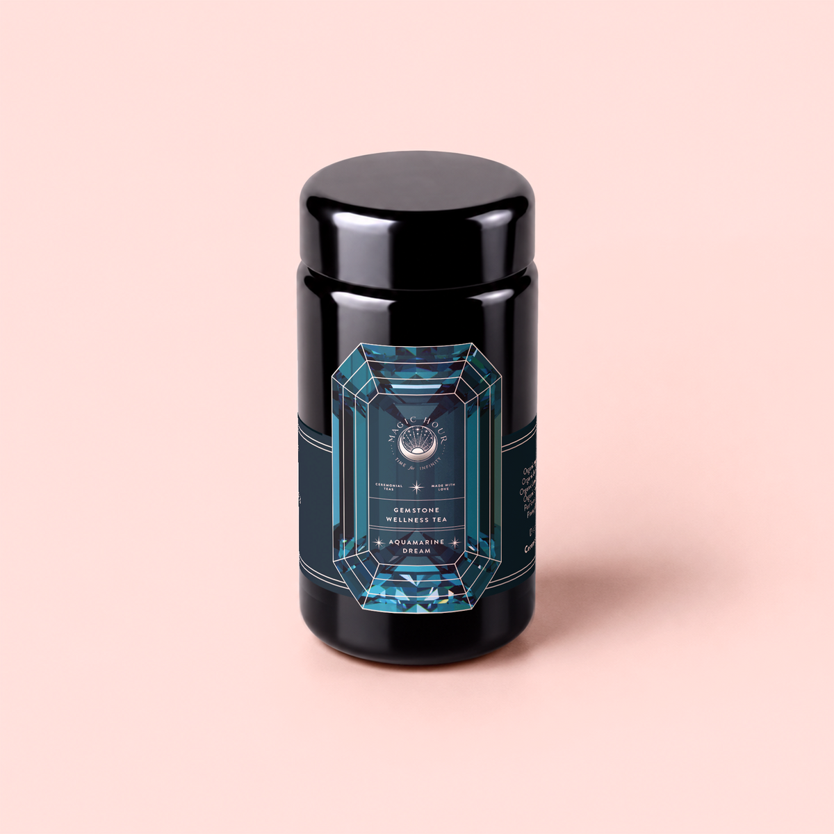 A black cylindrical container with a geometric blue label, set against a light pink background. The intricate label design and text suggest it is Aquamarine Dream – Soothing Herbal Ayurvedic Adrenal Tonic, an adaptogen sleep blend, though the finer details remain out of focus.