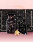 The Aquarius Astrology Tea Gift Set includes an Aquarius-themed bottle, Opal Moon Ritual Tea, an Opalite Moon Tea Strainer, all packaged in a large decorative box with star and moon motifs on a pink gradient background.