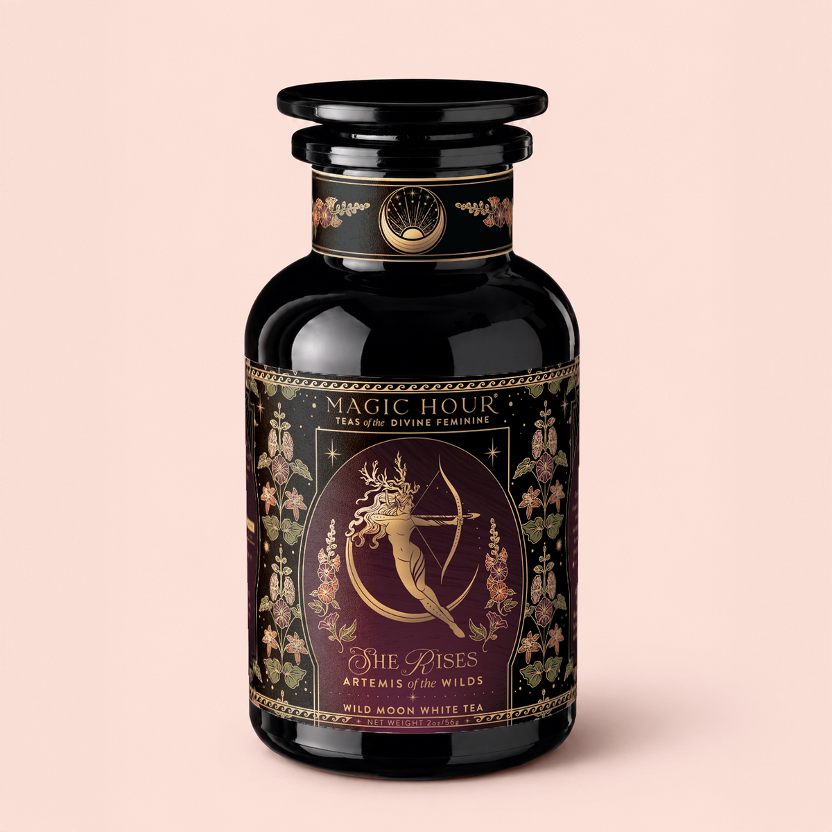 A beautifully designed black tea canister labeled “Artemis of the Wilds: Wild Moon White Tea” features ornate floral patterns and an illustration of Artemis, the archer. Inside is a celestial blend of moonlight white tea delicately infused with hints of butterfly pea flower.