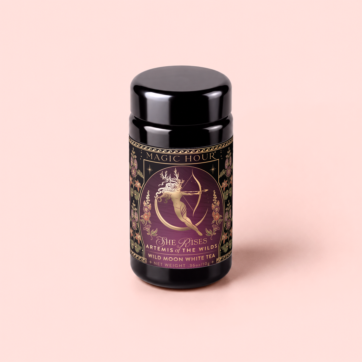 A black tea canister labeled “Artemis of the Wilds: Wild Moon White Tea” features a gold-illustrated woman with a bow and arrow, surrounded by floral designs and delicate butterfly pea flower accents on a mauve background.