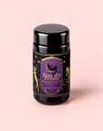 A tea canister labeled “Black Cat Brownie: Decadent Chocolate Puerh Blend with Vanilla & Hazelnut” features a mystical purple and gold design with a black cat, crescent moon, and ornate decorations set against a light pink background. Inspired by the luxurious flavors of chocolate puerh blended with vanilla and hazelnut, this canister promises an enchanting brew as captivating as its appearance.