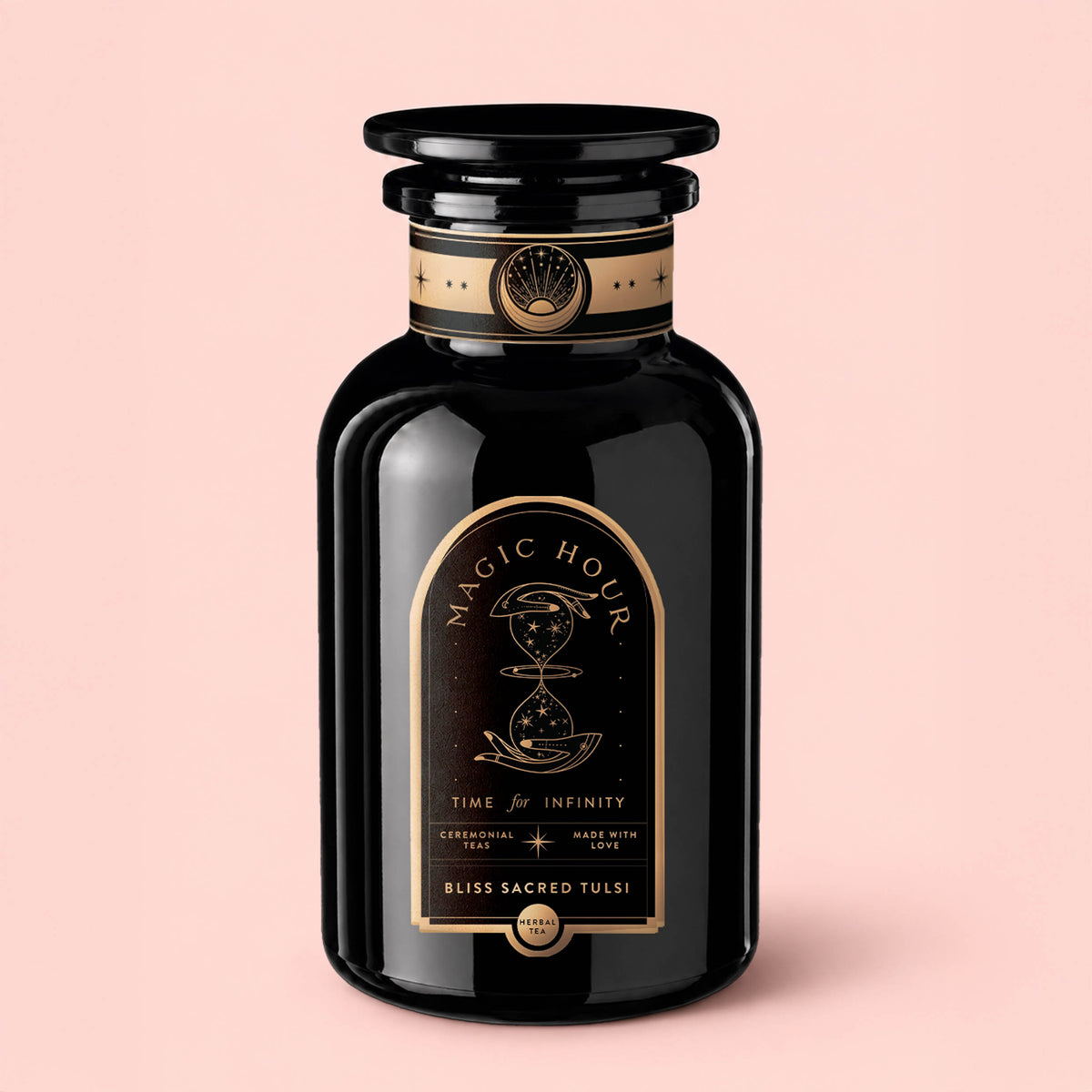 A black glass jar labeled “Bliss: Sacred Tulsi Adaptogen Tea” with gold accents, adorned with an illustration of pouring liquid and the phrases “Time for Infinity” and “Magic Hour,” sits atop a pale pink background—evoking the calming properties of Holy Basil, traditionally used to soothe the nervous system.