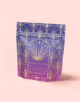 A stand-up pouch of Blue Beauty: Butterfly Pea Flower Powder Boost features a purple-to-pink gradient, gold art deco patterns, starburst design, and elegant text—perfect for supporting collagen production.