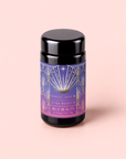 A black jar labeled “Blue Beauty: Butterfly Pea Flower Powder Boost,” featuring a decorative blue and gold art deco design, is set against a light pink background and showcases the beauty-boosting benefits of butterfly pea flower powder, renowned for supporting collagen production.