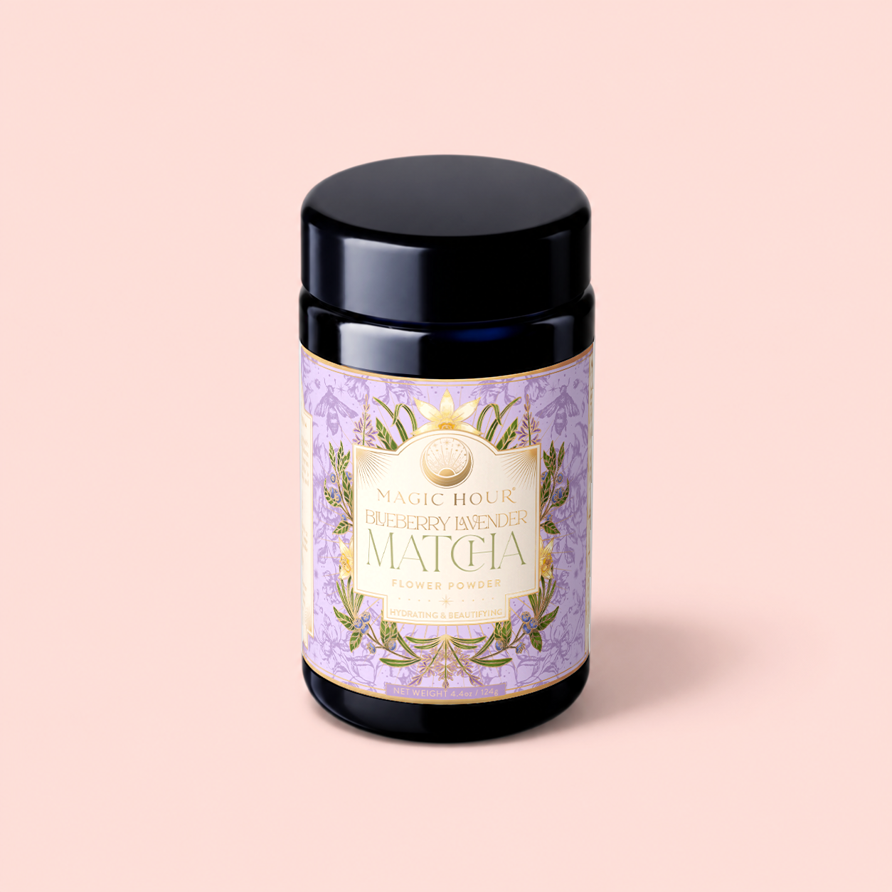 A dark jar with a lavender and gold label reading "Flower Powder: Blueberry Lavender Matcha" sits on a pale pink background, evoking the soothing essence of blueberry matcha and calming aromatherapy.