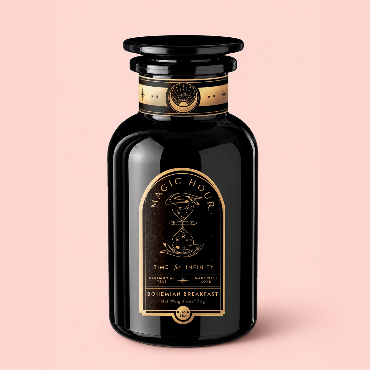 A glossy black tea jar labeled “Magic Hour” features a celestial gold design and the phrases “Time for Infinity” and “Bohemian Breakfast” set against a pale pink background, offering Bohemian Breakfast Vanilla Puerh Black Tea for Digestion &amp; Energy as an organic black tea that’s perfect as a coffee alternative.
