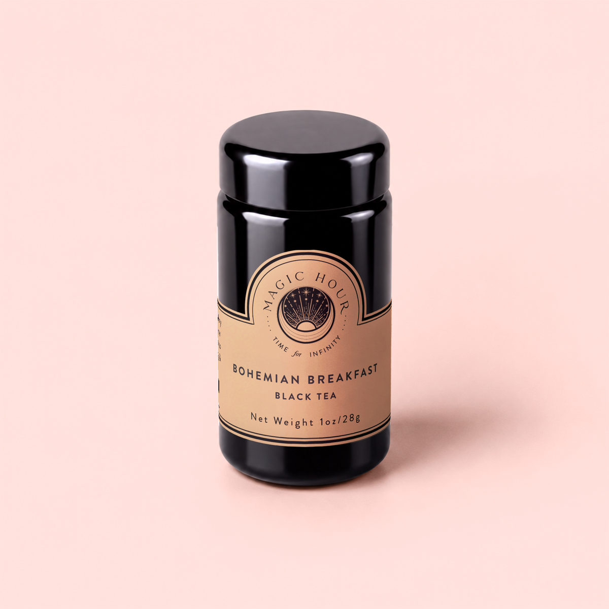 A black canister of Magic Hour Bohemian Breakfast Vanilla Puerh Black Tea for Digestion &amp; Energy is set against a pale pink background. The beige label with gold details displays the product name and weight of 1oz (28g), making it an elegant coffee alternative for your morning ritual.