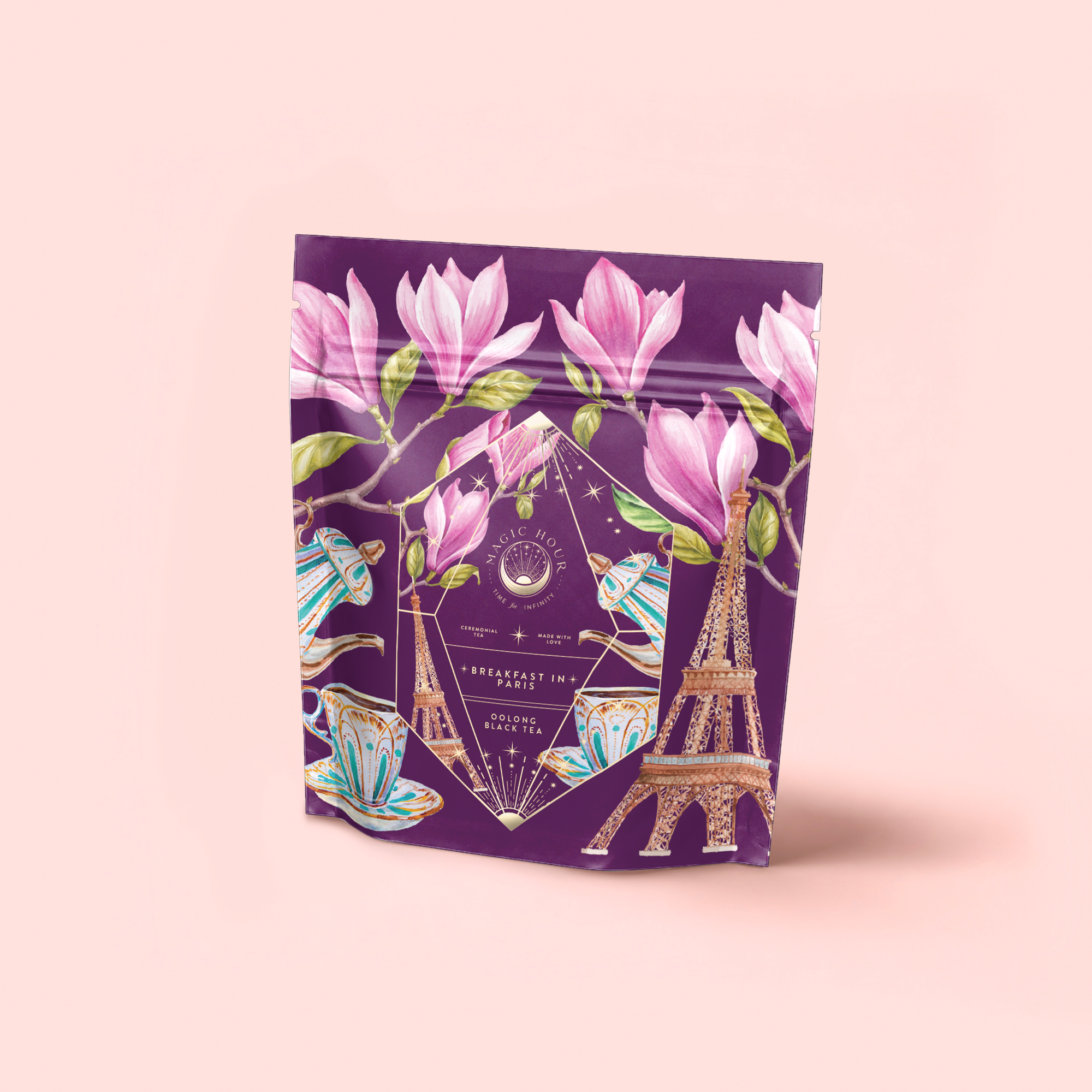 The "Breakfast in Paris-Oolong Black Tea Scented with Fruits & Flowers of Secret Parisian Gardens" comes in a purple package adorned with magnolia flowers, teacups, teapots, and a golden Eiffel Tower on a pale pink background.
