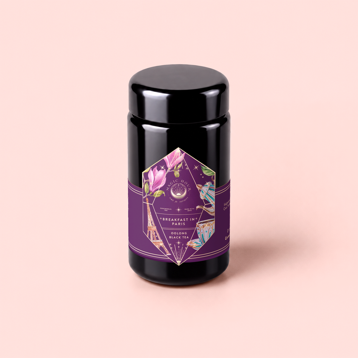 A black tea canister adorned with a purple and floral geometric label reading “Breakfast in Paris-Oolong Black Tea Scented with Fruits &amp; Flowers of Secret Parisian Gardens,” set against a pale pink backdrop—this romantic blend encapsulates the essence of an authentic Parisian black tea experience.