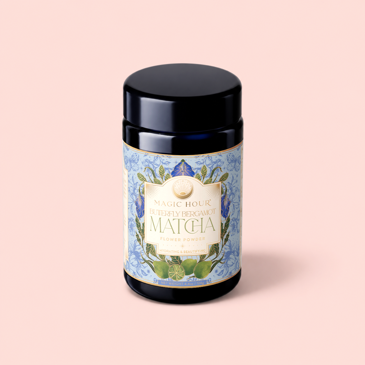A dark jar labeled "Flower Powder: Butterfly Bergamot Matcha," adorned with blue floral designs, rests against a pastel pink background. This exquisite blend unites ceremonial matcha with butterfly pea flower and vibrant notes of bergamot to create a truly enchanting tea experience.