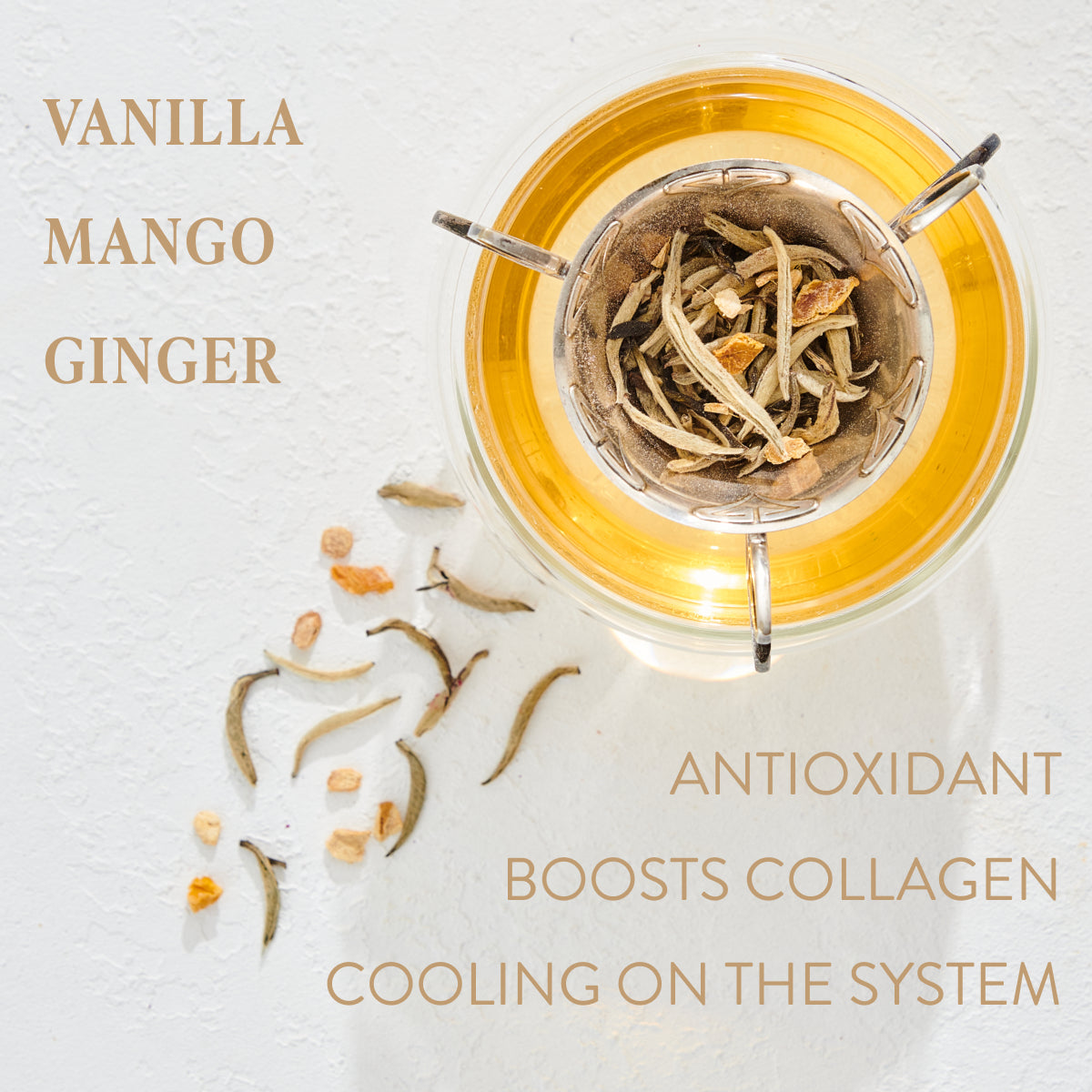 A glass cup filled with golden tea and loose leaf tea around it is shown from above. The text on the left reads "Vanilla, Mango, Ginger," and on the right it reads "Organic Tea, Boosts Collagen, Cooling on the System." Indulge in Magic Hour Cancer: Queen of Cool Mango-Ginger-Cream White Tea for a truly enriching experience.