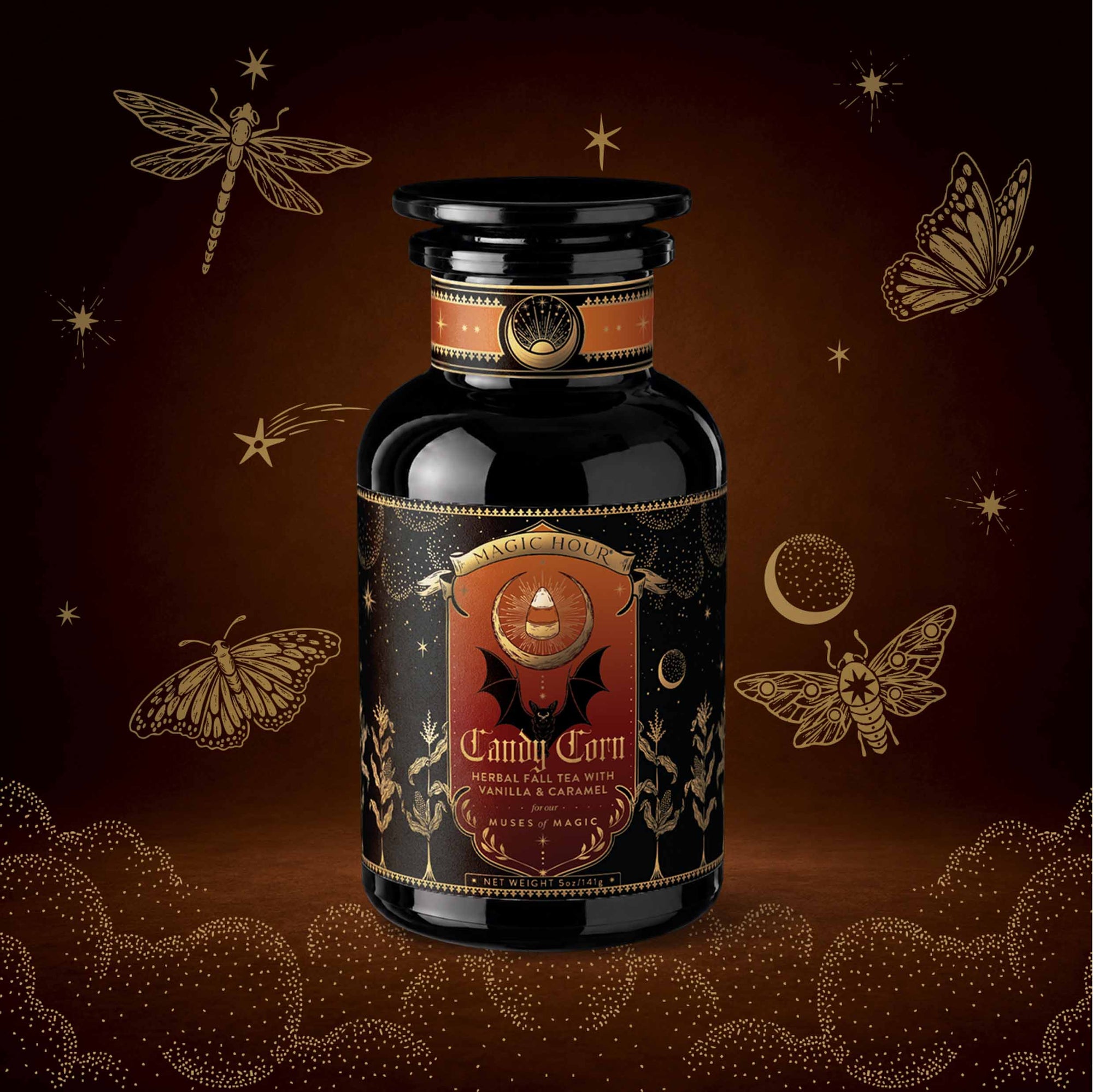 A black apothecary-style jar labeled “Candy Corn: Herbal Fall Tea with Vanilla & Caramel” sits on a brown background adorned with gold stars, a crescent moon, dragonflies, and moths—making this caffeine-free herbal blend the perfect cozy companion for crisp autumn nights.