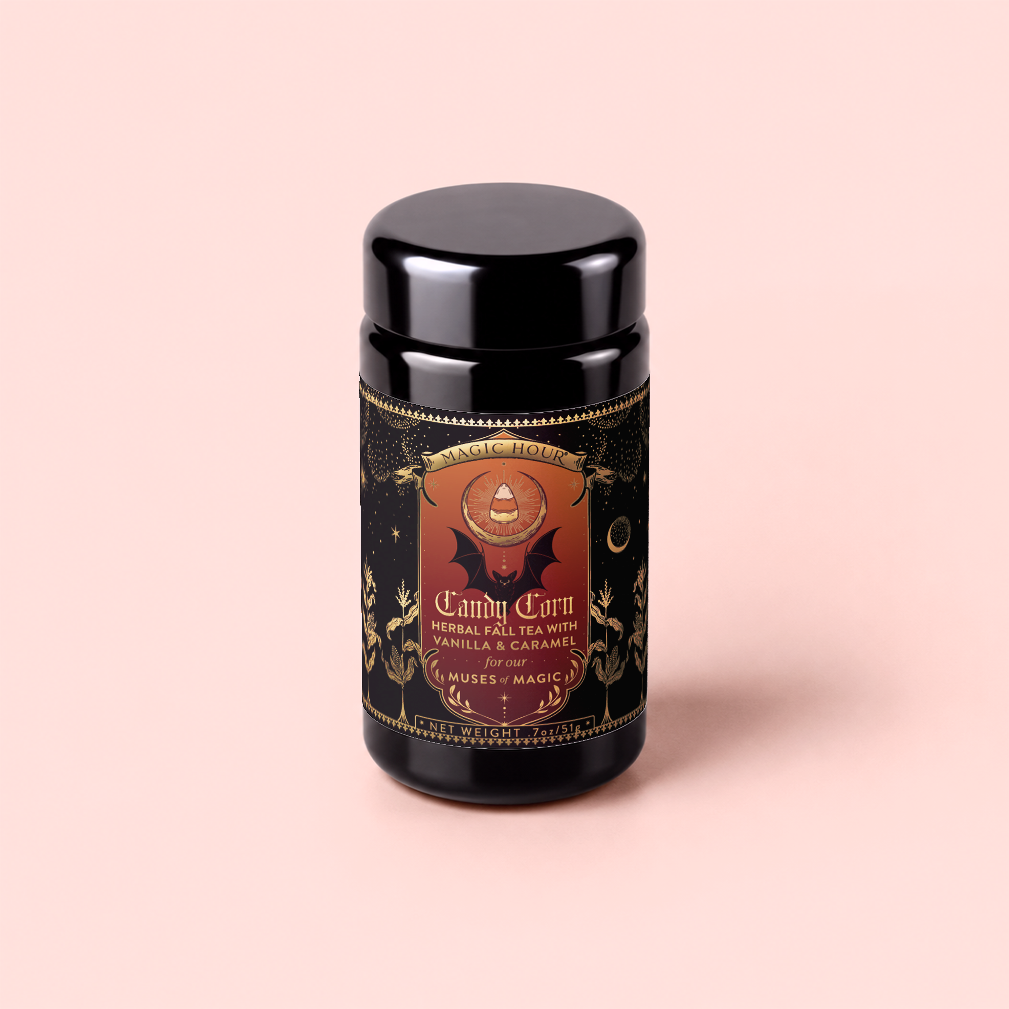 A black tea canister with a gold and red label reads “Candy Corn: Herbal Fall Tea with Vanilla &amp; Caramel.” The design showcases celestial and mystical imagery on a light pink background, making this caffeine-free herbal tea blend the perfect Halloween treat for cozy autumn evenings.