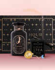 A black starry "Magic Hour" gift box holds the Capricorn Astrology Tea Gift Set, including a Capricorn tea jar, Opal Moon Ritual Tea, and an Opalite Moon Tea Strainer, set on a pink gradient background.