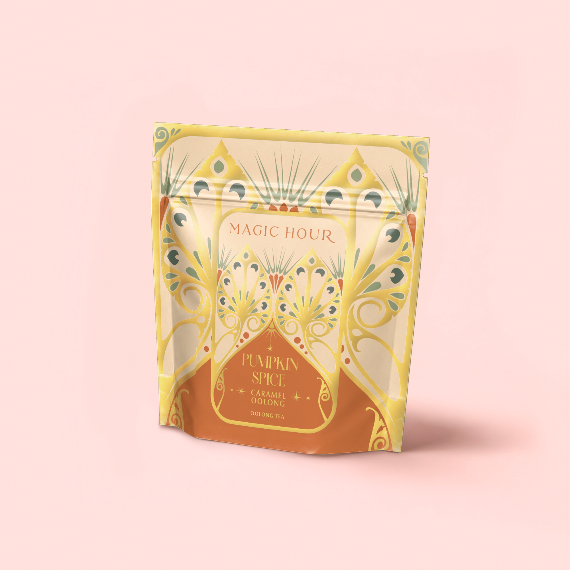 A decorative gold and orange stand-up pouch labeled "Pumpkin Spice Caramel Oolong" features an ornate, art nouveau-inspired design. This fall harvest pumpkin caramel tea is set against a soft pink background.