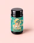 A black jar labeled “Compassion: Quan Yin Original Style Oolong,” featuring an illustrated woman and floral design on a pastel pink background, evokes tranquility—ideal for savoring this signature oolong tea.