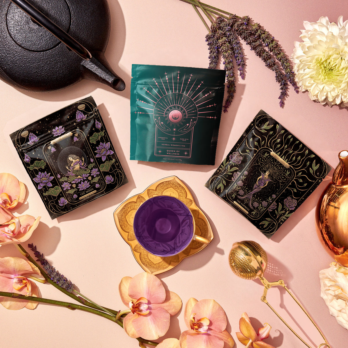 A Cycle Harmony Tea Sampler Set featuring three pouches of adaptogenic tea arranged around an empty teacup, accompanied by a teapot, a tea infuser, lavender sprigs, and flowers for hormonal harmony.