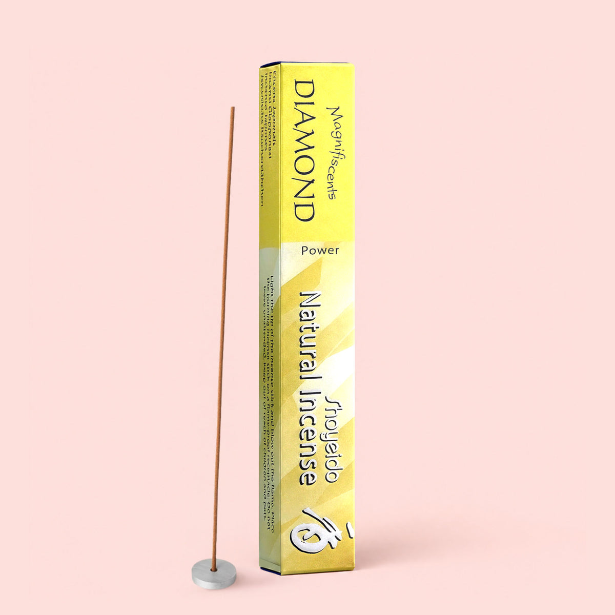 A yellow box labeled “Diamond Incense” stands upright, its fragrance promising a calming ambiance, next to a single incense stick held in a small white holder, set against a pale pink background.