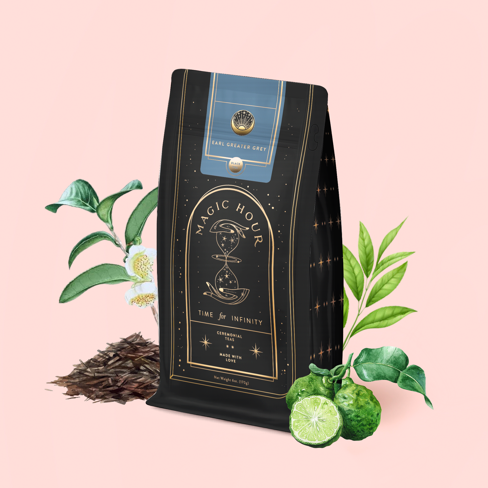 A bag of Earl Greater Grey: Tea for the Bright &amp; Bold rests on a pink background, surrounded by tea leaves, bergamot, and green foliage. The packaging showcases gold celestial-themed graphics and elegant labeling.